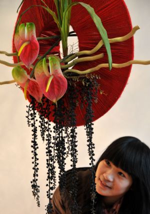  A visitor appreciates ikebana works during the 2nd Wuhu ikebana contest held in Wuhu city, east China's Anhui Province, Nov. 29, 2009. Fifty-eight contestants took part in the ikebana theoretics and skill contest on Sunday. The first prize winner of the contest will receive skill topmost master certificate and trophy from local labor administrative department. 