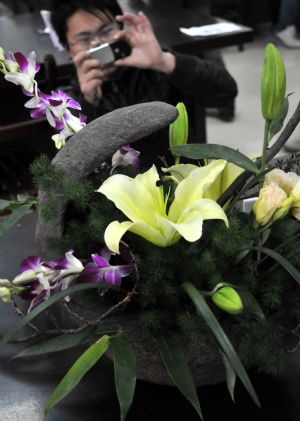 A visitor takes pictures of ikebana works with his mobile phone during the 2nd Wuhu ikebana contest held in Wuhu city, east China's Anhui Province, Nov. 29, 2009. Fifty-eight contestants took part in the ikebana theoretics and skill contest on Sunday. The first prize winner of the contest will receive skill topmost master certificate and trophy from local labor administrative department. 