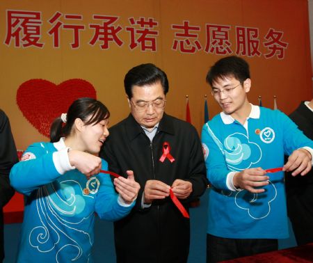 Chinese President Hu Jintao (C) makes a red ribbon while taking part in a gathering of AIDS prevention volunteers in Beijing, capital of China, Nov. 30, 2009, a day before the 22nd World AIDS Day. Chinese Vice Premier Li Keqiang (3rd, R) also attended the gathering. (Xinhua/Pang Xinglei) 