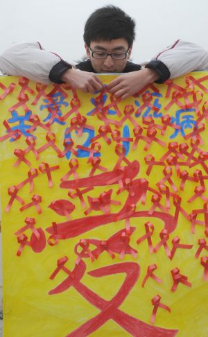  A volunteer sticks AIDS symbol onto a poster during an AIDS-awareness event inside Sichuan University in Chengdu, capital of southwest China&apos;s Sichuan Province on Dec. 1, 2009, World AIDS Day. (Xinhua/Jiang Hongjing) 