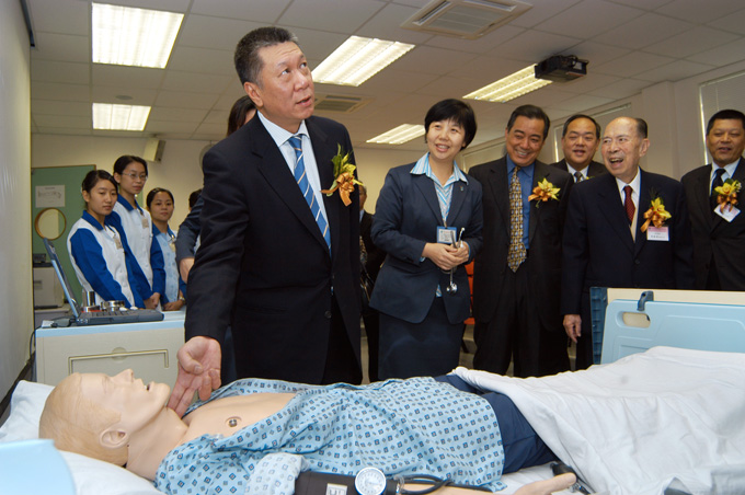 Former Chief Executive of the Macao Special Administrative Region Ho Hau Wah shows great interest in a model patient. Ho visited Kiang Wu Nursing College of Macao on Nov. 28, 2003.