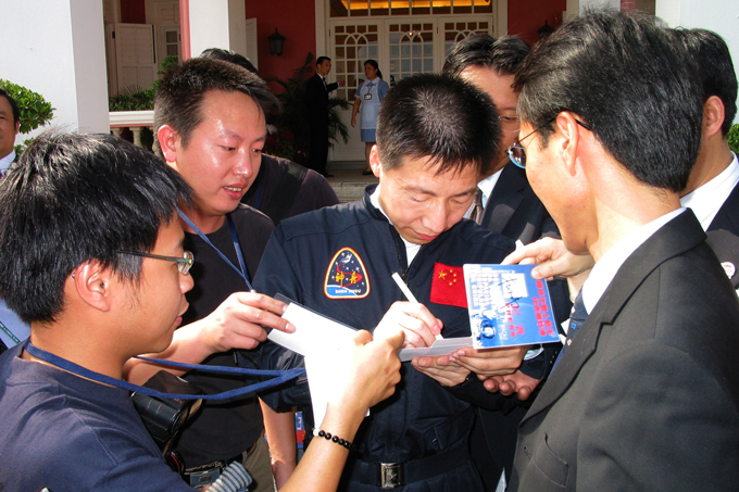 Journalists ask China's first astronaut, Yang Liwei (C), to sign for them. Yang visited Macao in November 2003.
