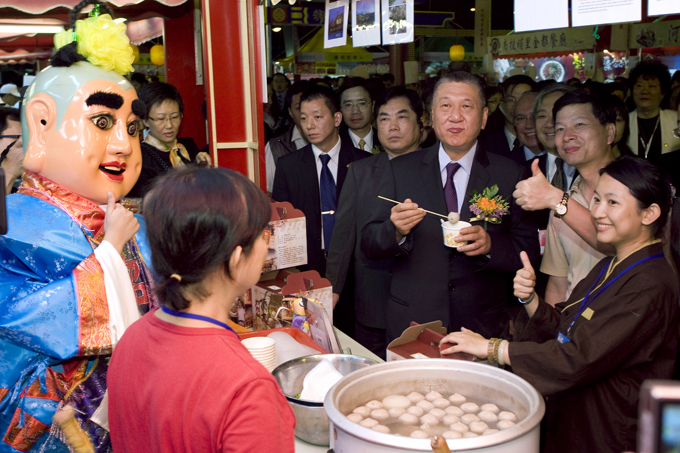 Former Chief Executive of the Macao Special Administrative Region Ho Hau Wah taste-tests some food at a snake-meat store during an annual food festival.