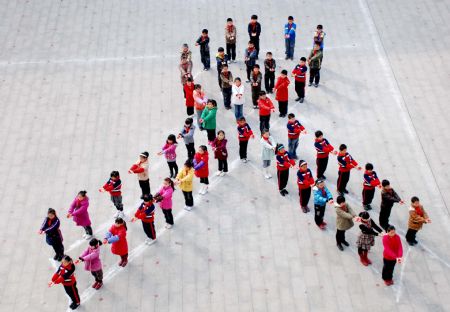About 50 students holding red ribbons make up a pattern of a red ribbon at No.1 Primary School of Leping City, east China&apos;s Jiangxi Province, Dec. 1, 2009, to greet the World Aids Day. (Xinhua/Zhu Dingwen)