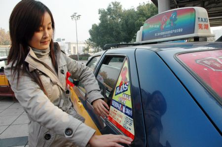 A taxi driver pastes an AIDS awareness publicity picture on her taxi in Wuhu, east China&apos;s Anhui Province, Dec. 1, 2009. (Xinhua/Tu Zhiqin)