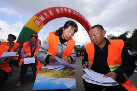 A volunteer helps a migrant worker (R) to fill in a questionnaire during an AIDS-awareness event in Kunming, capital of southwest China&apos;s Yunnan Province, Dec. 1, 2009, World AIDS Day. (Xinhua/Qin Qing)