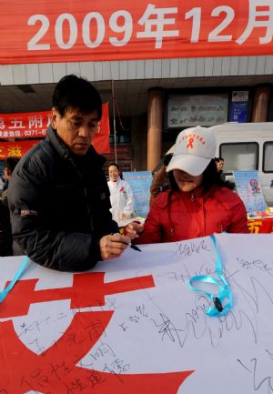 A passenger writes down his signature on a poster during an AIDS-awareness event in Zhengzhou, capital of central China&apos;s Henan Province, Dec. 1, 2009, World AIDS Day. (Xinhua/Zhu Xiang)