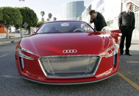 California governor Arnold Schwarzenegger (background) tours alternative fuel vehicles during a preview at the 2009 L.A. Auto Show as he inspects an Audi E-tron electric concept car in Los Angeles, California December 1, 2009. 