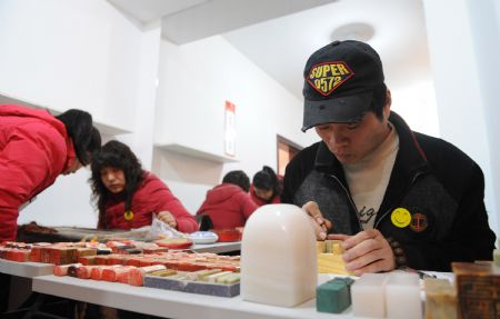 Deaf-mute man Cao Jinliang (R) studys seal cutting at a disability service supermarket in Zhengzhou, capital of central China&apos;s Henan Province, Dec. 3, 2009. The supermarket founded by local disabled persons&apos; federation to assist disabled persons in getting jobs opened on Thursday. Activities were held on Dec. 3 all over China to mark the 18th World Disability Day. 