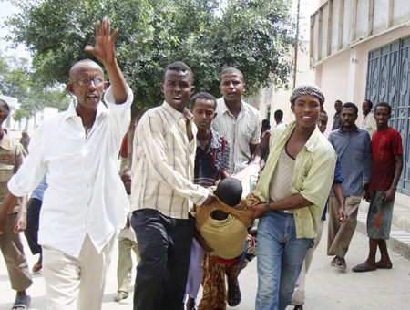 A wounded man is carried by residents after an explosion at the Hotel Shamo in Mogadishu December 3, 2009. The explosion tore through a graduation ceremony at the hotel on Thursday and killed at least 14 people including three government ministers, witnesses and senior government sources said.