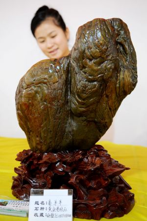 A girl enjoys a rare stone in a rare stone fair in Hezhou, southwest China&apos;s Guangxi Zhuang Autonomous Region, Dec. 3, 2009.(Xinhua/Huang Xuhu)