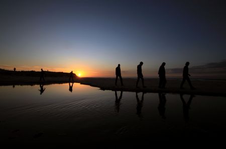 Palestinian men walk on the seashore at sunset in Gaza City, Dec.5, 2009.[Xinhua/Wissam Nassar]