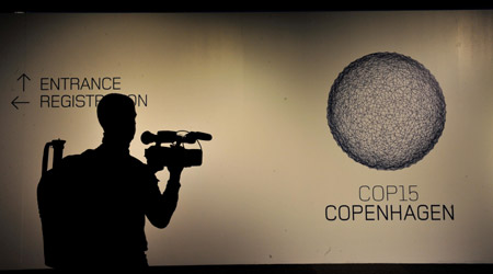 A cameraman films a billard of the 15th United Nations Climate Change Conference (COP15) at Bella Center in Copenhagen, capital of Demark, Dec. 6, 2009. The conference will be held from Dec. 7 to 18. [Xu Suhui/Xinhua]