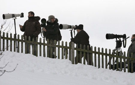 Photographers stand in the snow behind a fence near the chalet &apos;Milky Way&apos; of Oscar-winning film director Roman Polanski in the Swiss mountain resort of Gstaad December 6, 2009. [Xinhua/Reuters] 