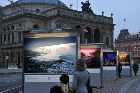 People look at pictures on display during a photo exhibition on climate change in Danish capital Copenhagen on Dec. 6, 2009. The United Nations Climate Change Conference 2009 will open in Copenhagen on Monday. [Xu Suhui/Xinhua] 