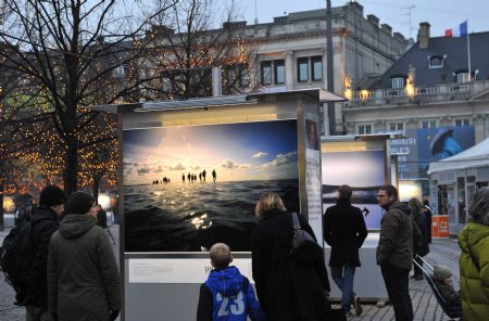 People look at pictures on display during a photo exhibition on climate change in Danish capital Copenhagen, on Dec. 6, 2009. The United Nations Climate Change Conference 2009 will open in Copenhagen on Monday. [Xu Suhui/Xinhua] 