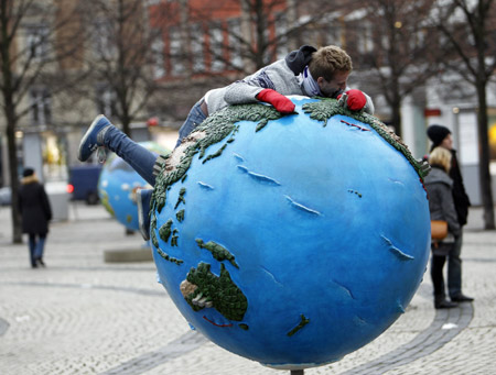 A man lies on a globe which is a part of an installation in downtown Copenhagen December 6, 2009. Copenhagen is the host city for the United Nations Climate Change Conference 2009, from December 7 until December 18.[Xinhua/Reuters]