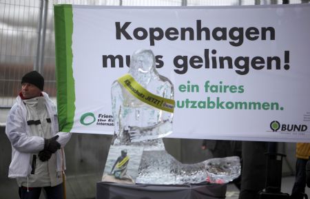 An environmental activist holds up a banner in front of a melting ice sculpture, outside the congress centre, before the opening of the United Nations Climate Change Conference 2009 in Copenhagen December 7, 2009.[Xinhua/Reuters]
