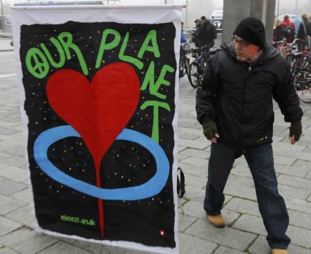 A man looks at a banner as he walks past, outside the congress centre before the opening of the United Nations Climate Change Conference 2009 in Copenhagen December 7, 2009. [Xinhua/Reuters]