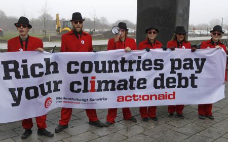 Members of environmental activist group Act!onaid, dressed as &apos;climate debt agents&apos;, hold up a banner outside the congress centre, before the opening of the United Nations Climate Change Conference 2009 in Copenhagen December 7, 2009.[Xinhua/Reuters]