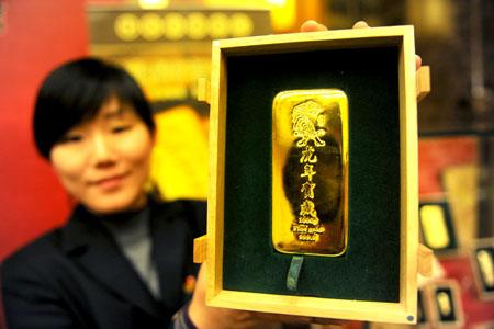 A salesclerk shows a gold bar with the sign of tiger at the Caibai department store in Beijing, capital of China, Dec. 7, 2009. The gold bars carrying the sign of tiger ranging from 50 grams, 100 grams, 200 grams, 500 grams and one kilogram will be on sale at the store Dec. 8. The year of 2010 is the Year of Tiger according to the Chinese traditional lunar calendar.[Xinhua]