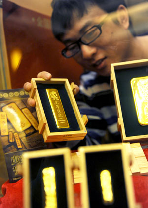 A salesclerk arranges gold bars with the sign of tiger at the Caibai department store in Beijing, capital of China, Dec. 7, 2009.[Xinhua]