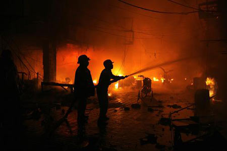 Fire fighters put out a blaze after a bomb explosion at a market in Lahore Dec. 7, 2009. [Xinhua/Reuters]