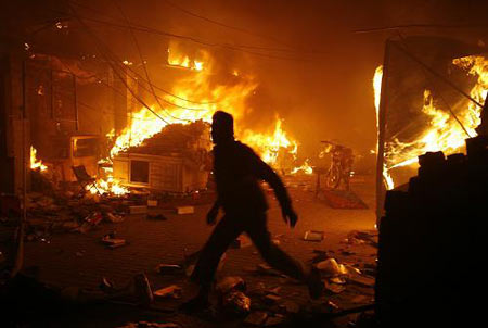 A man runs past a blaze after a bomb explosion at a market in Lahore Dec. 7, 2009. [Xinhua/Reuters]