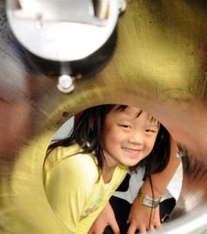 A child looks through a cannon bore while visiting the Chinese missile frigate &apos;Xuzhou&apos; at a port in the state of Selangor of Malaysia Dec. 7, 2009. [Li Xueqing/Xinhua]