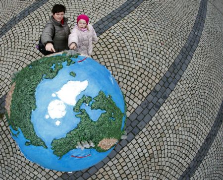 People look at a globe which is a part of of an installation in downtown Copenhagen December 6, 2009. Copenhagen is the host city for the United Nations Climate Change Conference 2009 which starts from December 7 until December 18.(Xinhua/Reuters Photo)