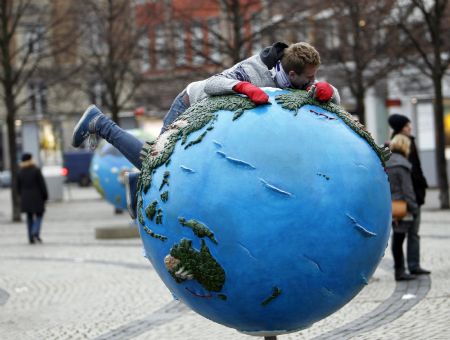 A man lies on a globe which is a part of an installation in downtown Copenhagen December 6, 2009. Copenhagen is the host city for the United Nations Climate Change Conference 2009, from December 7 until December 18.(Xinhua/Reuters Photo)