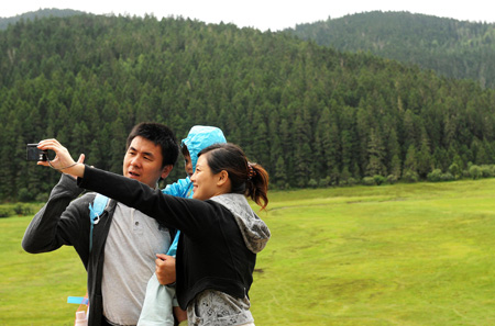 The picture taken on Oct. 13, 2009 shows tourists taking pictures at the Pudacuo National Park in Deqen Tibetan Autonomous Prefecture, southwest China's Yunnan Province. The 2000-square-kilometer national park maintains the integrity of virgin forest ecosystem. The local government has taken several measures to balance the environment protection and tourism promotion within the region. (Xinhua/Lin Yiguang) 