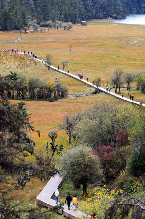 The picture taken on Oct. 13, 2009 shows tourists walking at the Pudacuo National Park in Deqen Tibetan Autonomous Prefecture, southwest China's Yunnan Province. (Xinhua/Lin Yiguang)