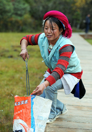 The picture taken on Oct. 13, 2009 shows a cleaner of the Tibetan ethnic group picking up garbage at the Pudacuo National Park in Deqen Tibetan Autonomous Prefecture, southwest China's Yunnan Province. (Xinhua/Lin Yiguang) 