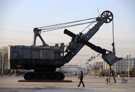 A man walks past a coal excavator on display at the National Mine Park in Fuxin, Liaoning province November 21, 2009. Fuxin, in China's northeast Liaoning Province, which relied mainly on mining in the past, is the first pilot city identified by the State Council to transform its economy, Xinhua News Agency reported.[