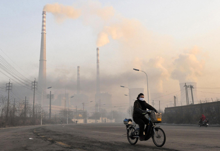 A man rides a bike past a heat power plant in Fuxin, Liaoning province November 23, 2009. Fuxin, in China's northeast Liaoning Province, which relied mainly on mining in the past, is the first pilot city identified by the State Council to transform its economy, Xinhua News Agency reported.[