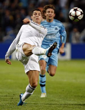 Real Madrid&apos;s Cristiano Ronaldo (L) kicks the ball as Olympique Marseille&apos;s Gabriel Heinze (R) looks on during their Champions League soccer match at the Velodrome stadium in Marseille December 8, 2009. [Xinhua/Reuters]