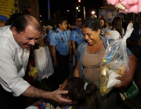 Nicaraguan President Daniel Ortega (L) smiles to a girl while offering free food to local citizens in Managua, capital of Nicaragua, Dec. 7, 2009.[Xinhua]