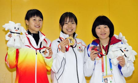 Silver medalist Yi Siling (L) of China shows the medal with gold medalist Konomoto Maki(C) of Japan and bronze medalist Gu Sura of South Korea during the awarding ceremony for the women&apos;s final of the 10m Air Rifle in the 2009 East Asian Games at South China Athletic Association in Hong Kong on Dec. 8, 2009. [Xinhua]