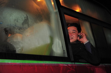 A resettler calls his friends to say goodbye on a passenger vehicle in Junxian County, Danjiangkou City of central China&apos;s Hubei Province December 8, 2009.[Xinhua]