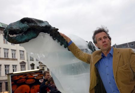 British explorer Pen Hadow touches an ice sculpture of a polar bear as it melts to reveal a bronze skeleton in Copenhagen Dec. 8, 2009. The ice sculpture had been placed in downtown Copenhagen since Dec. 5, 2009, to draw the attention of people about the rising temperature. [Xinhua]