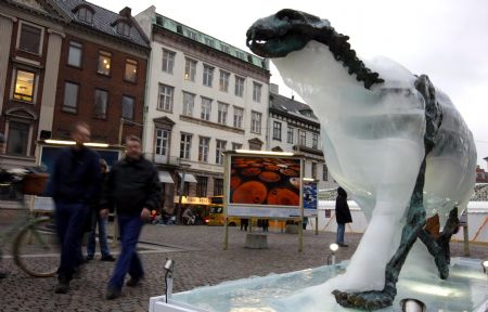 People pass by an ice sculpture of a polar bear as it melts to reveal a bronze skeleton in Copenhagen Dec. 8, 2009. [Xinhua]