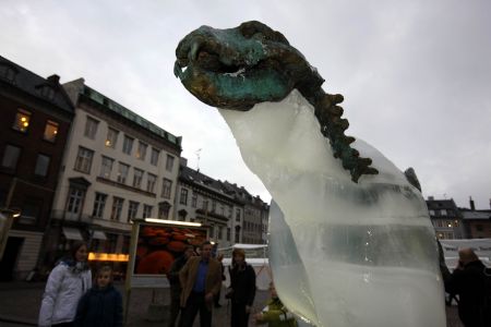 People watch an ice sculpture of a polar bear as it melts to reveal a bronze skeleton in Copenhagen Dec. 8, 2009. [Xinhua]