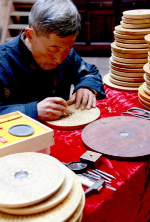 Handicraftsman Wu Shuisen, the seventh-generation inheritor of the making skills of Wuluheng Compass, tests a Wuluheng Compass in Wan'an Town of Xiuning County, east China's Anhui province, Dec. 3, 2009. [Shi Guangde/Xinhua]