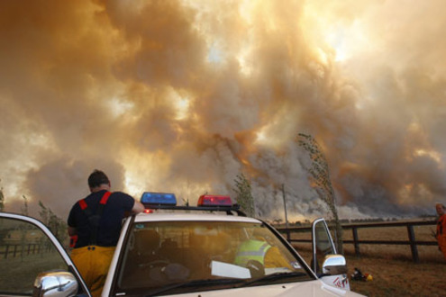 A fireman climbs down from his truck as a bushfire approaches the town of Labertouche, 90km (56 miles) east of Melbourne February 7, 2009. Aircraft dropped water bombs on raging Australian bush fires on Saturday as a 