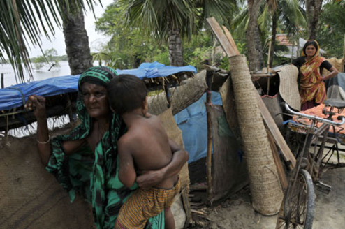A woman holding a child stands outside a makeshift shelter in Khulna, southwestern Bangladesh, on May 28, 2009. At least 131 people died and 1,123 people are still missing after the cyclone Aila hit Bangladesh's southwestern coast on Monday, officials said on Thursday.