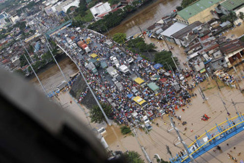 People wait for rescue on a submerged bridge in Cainta of Rizal Province, the Philippines, on Sept. 27, 2009. At least 51 people were killed while 21 others remain missing as tropical storm Kestana hit the Philippines and brought massive flood on Saturday, the government disasters relief agency said Sunday. (Xinhua/Stringer)