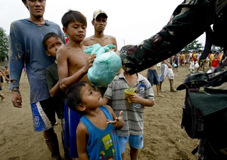 Flood victims line up to get food and clothes at a village in Rodriguez, Rizal province, the Philippines, Sept. 30, 2009. Kestana, locally known as Ondoy, swept through the central Luzon region last Saturday. The epic rainfall brought by the storm caused massive flooding and landslides. Two hundred and forty-six people were killed, 42 remain missing while nearly 700,000 people fled their flooded homes to stay in either evacuation centers or with host families.
