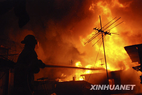 A fireman tries to put out a fire in the heart of Metro Manila, capital of the Philippines, Dec. 10, 2009. Local reports said that at least two people were killed in the fire. [Jon Fabrigar/Xinhua] 