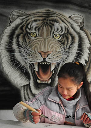 A middle school student draws a tiger painting in a studio in Wanggongzhuang Village of Minquan County, central China&apos;s Henan Province, Dec. 10, 2009. In Wanggongzhuang Village, over 700 painters create more than 60,000 tiger paintings every year, with an output value of 25 million RMB (about 3.7 million US dollars). The limners are expediting the work for more tiger paintings to meet the demand of the market, as the next year will be the year of tiger on Chinese calendar.[Xinhua]